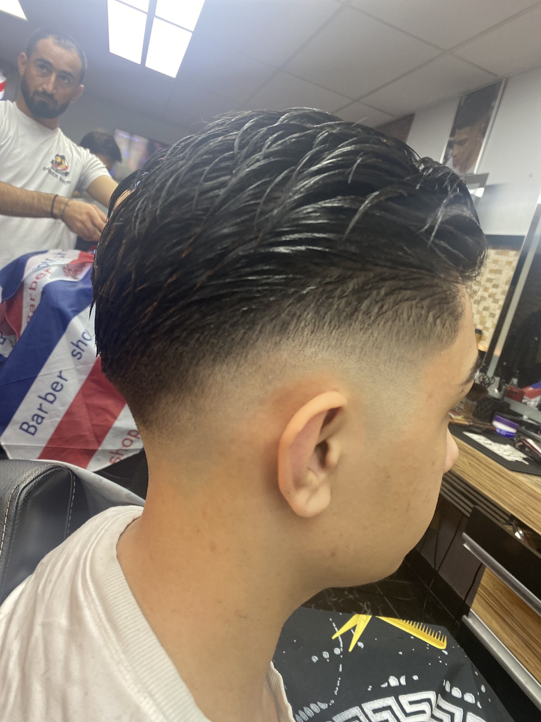 Een strakke fade met lengte erop, van opzij gezien, in de stoel bij Barber Adwar